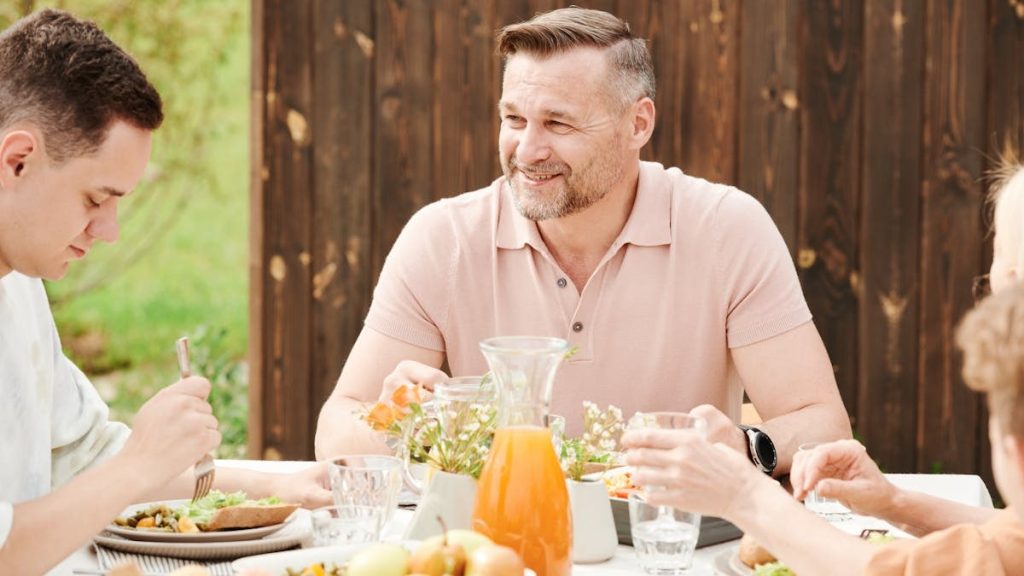 A cheerful family enjoying an outdoor meal together in a warm setting.