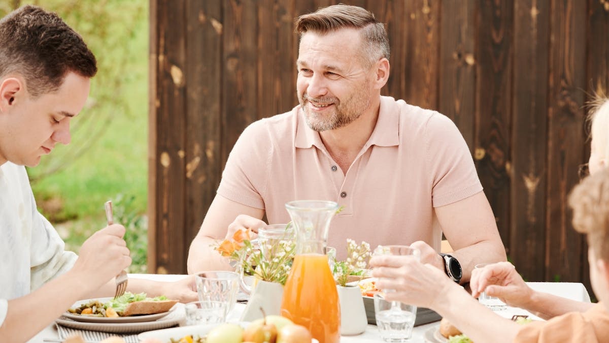 A cheerful family enjoying an outdoor meal together in a warm setting.